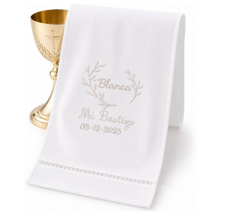 Pañuelo de bautizo blanco bordado con nombre y fecha junto a un cáliz dorado