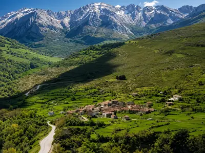 Vista del pueblo de San Sebastián de Garabandal entre prados verdes, con los Picos de Europa al fondo